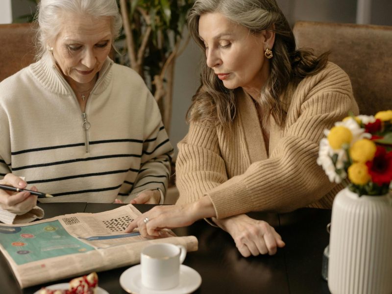 Elderly women solving a crossword puzzle, fostering friendship and mental stimulation indoors.